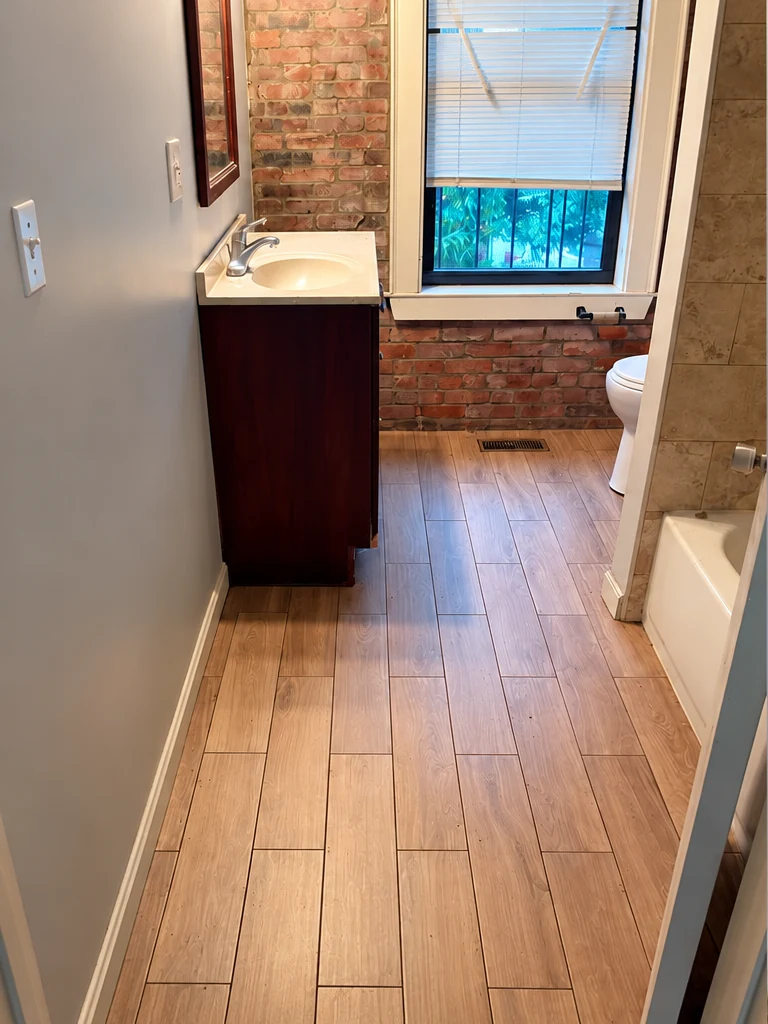 Brick bathroom before demolition, with vanity, flooring and bath fittings in place